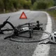 Bici rotta e casco sull'asfalto dopo un incidente