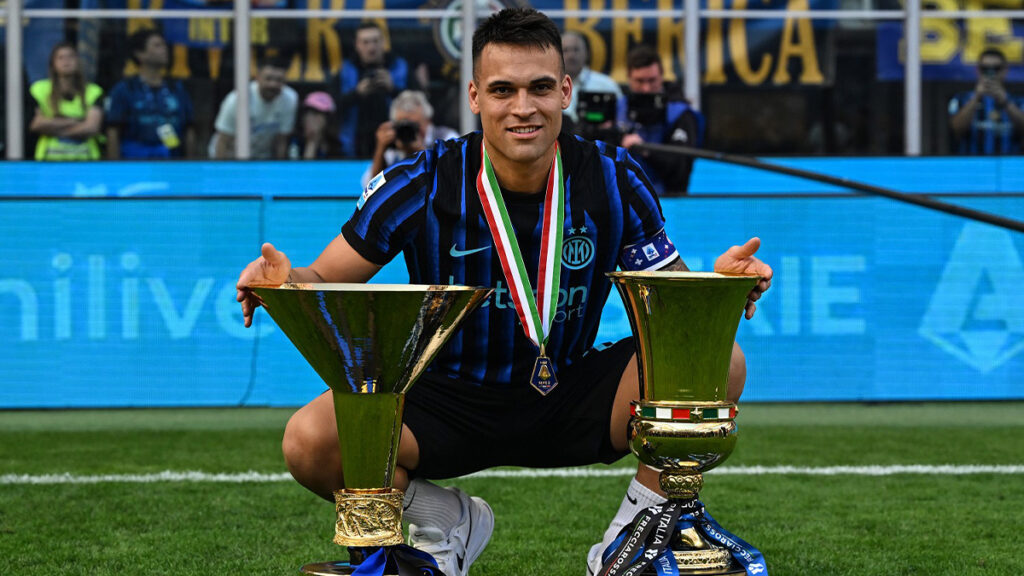Il capitano dell'Inter, Lautaro Martinez, in posa con il trofeo dello scudetto e quello della Coppa Italia